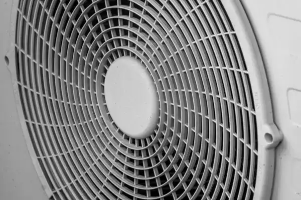 Close-up of a circular fan grille with a grid pattern, part of an electrical appliance.