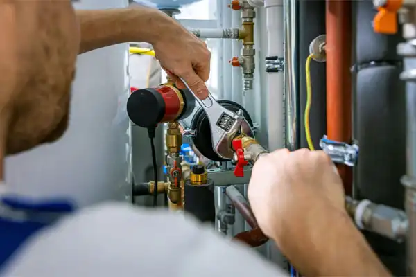 Person using a wrench to adjust a pipe in a plumbing system.